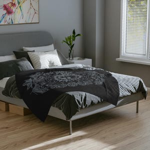 May include: Black and white mandala patterned throw blanket on a gray bed with white pillows.