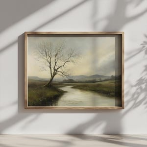 Puede incluir: Pintura de paisaje enmarcada que representa un río sinuoso a través de un campo, con un árbol desnudo a la izquierda. La obra de arte presenta tonos apagados de verde, marrón y gris, creando una estética vintage tranquila.