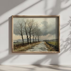 Puede incluir: Pintura de paisaje enmarcada que representa un camino rural bordeado de árboles desnudos bajo un cielo nublado. El camino está mojado y un muro de piedra bordea un campo verde. La obra de arte está en un marco de madera.