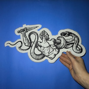 May include: Black and white embroidered patch of a man wrestling a snake. The man is holding a dagger in his right hand. The snake is wrapped around the man's body. The patch is on a blue background.