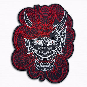 Könnte beinhalten: Ein schwarzer Aufnäher mit einem detaillierten Design eines roten Drachen und einer weißen Dämonenmaske. Der Körper des Drachen bildet einen Hintergrund für die Maske, mit komplizierten Linien und Details. Der Aufnäher hat einen gestickten Rand.