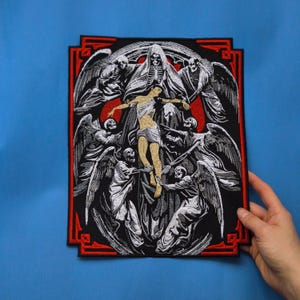 Könnte beinhalten: Gestickter Aufnäher mit einer religiösen Szene mit skelettartigen Figuren und Engeln. Das Design ist hauptsächlich schwarz und weiß, mit einem roten Rand. Die zentrale Figur ist eine Person mit ausgestreckten Armen, umgeben von anderen Figuren. Der Aufnäher ist rechteckig.
