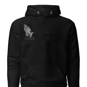 May include: Black hooded sweatshirt with a gray praying hands graphic and the word "Blessed" printed below.