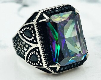 May include: A silver ring with a large, faceted, iridescent gemstone set in a detailed, black-accented design.