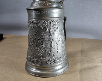 1928 pewter jug with hunting motifs, depicting hunters with ears of grain.