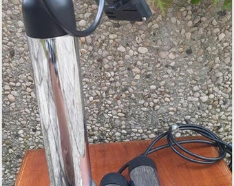 May include: Three chrome pendant lights with black cords and a black plug. The lights are cylindrical and have a rounded bottom. The lights are hanging from a wooden surface.
