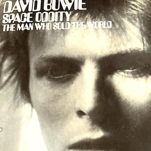 May include: A black and white photo of David Bowie, with the text "David Bowie Space Oddity The Man Who Sold The World" above his face.