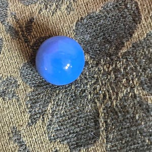 May include: A single, round, blue glass marble.