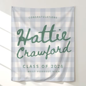 May include: A graduation banner with a denim gingham background and sage green text. The banner reads "Congratulations Hattie Crawford Class of 2026 West Forrest High."