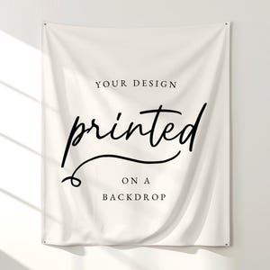 May include: A rectangular off-white fabric backdrop featuring black text. The text reads YOUR DESIGN in a simple serif font, followed by the word printed in a large black script font, and finally ON A BACKDROP in a simple serif font.