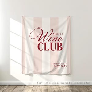 May include: A white and baby pink striped banner with the text "Alayna's Wine Club" in maroon lettering. The banner also includes the text "Sonoma County MAY 2025" in maroon lettering.