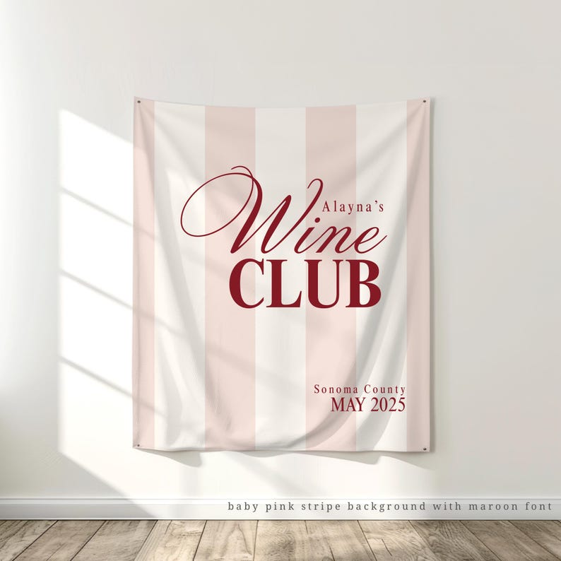May include: A white and baby pink striped banner with the text "Alayna's Wine Club" in maroon lettering. The banner also includes the text "Sonoma County MAY 2025" in maroon lettering.