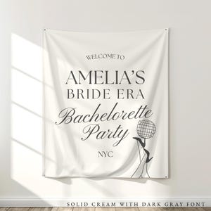 Bride Era Bachelorette Decorations: Off white cream fabric tapestry banner back drop with custom dark gray text in an upscale trendy and elegant font, customized with the bride's name, her bachelorette party theme and additional personalized details as well as a graphic to coordiate with the theme and decorations. Perfect for a welcome sign or photo background backdrop.