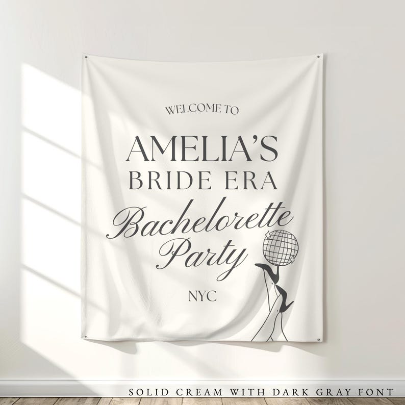 Bride Era Bachelorette Decorations: Off white cream fabric tapestry banner back drop with custom dark gray text in an upscale trendy and elegant font, customized with the bride's name, her bachelorette party theme and additional personalized details as well as a graphic to coordiate with the theme and decorations. Perfect for a welcome sign or photo background backdrop.