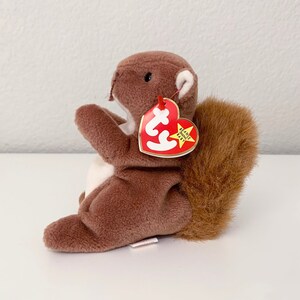 May include: Brown and white Beanie Baby squirrel plush toy with a red and white Ty tag that says "Beanie Babies" and has a star on it.
