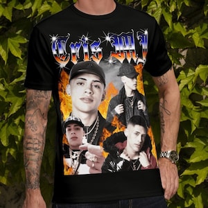 May include: A black t-shirt with a graphic print of a young man with a black cap and a gold chain. The graphic is surrounded by flames and the text "Chris MJ" is printed above the graphic.