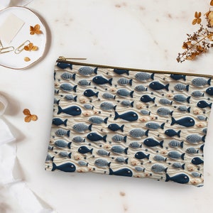May include: A white zippered pouch with a blue and white fish pattern. The pouch is made of fabric and has a zipper closure.