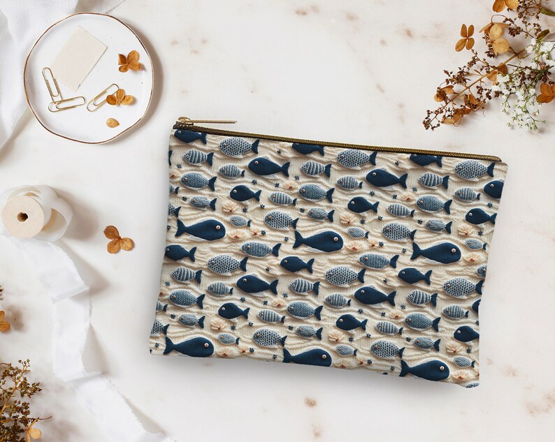 May include: A white zippered pouch with a blue and white fish pattern. The pouch is made of fabric and has a zipper closure.