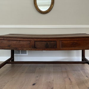May include: A dark brown wooden table with a curved top and a single drawer. The table has a simple design with straight legs and a single shelf.