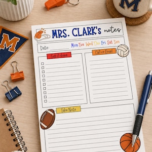 May include: A white notepad with the title "MRS. CLARK's notes" in blue. It features sections for tasks, calls, and notes, with illustrations of sports equipment. A pen, binder clips, and a mug are also visible on a wooden surface.