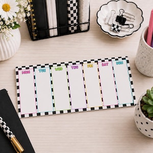 May include: A rectangular weekly planner notepad featuring a black and white checkered border. The planner is divided into seven vertical columns labeled with the days of the week from Monday to Sunday in colorful, bubble-style lettering.