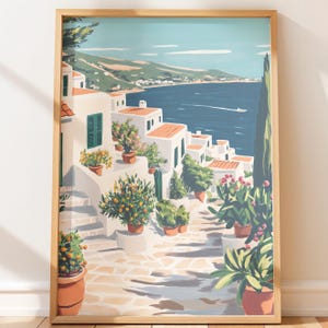 Puede incluir: Lámina artística enmarcada que representa una escena de un pueblo costero. Edificios blancos con tejados naranjas descienden por una ladera hacia un mar azul. Plantas en macetas y árboles bordean un camino de piedra. La obra está en un marco de madera.