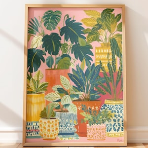 Puede incluir: Una impresión artística enmarcada que presenta una colección de plantas en macetas de varios tamaños y formas. Las plantas tienen hojas verdes y están en macetas coloridas con patrones. El fondo es de color rosa sólido.