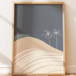May include: Framed art print featuring a minimalist desert landscape. The artwork depicts rolling sand dunes in shades of beige and tan, with a dark blue sky and two white palm trees. The print is encased in a natural wood frame.