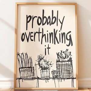 Puede incluir: Lámina artística enmarcada con la frase "probably overthinking it" en escritura negra. Debajo, dibujos lineales en blanco y negro de cactus en macetas. El marco es de color madera clara.