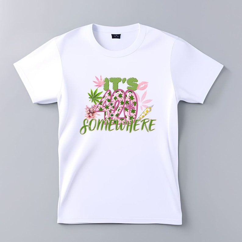 Op de afbeelding: Wit T-shirt met een roze en groene afbeelding met de tekst "It's 420 Somewhere".