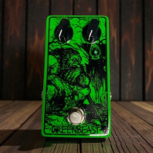 Könnte beinhalten: Ein grünes Gitarreneffektpedal mit schwarzen Knöpfen und einem Fußschalter. Das Pedal zeigt eine schwarze Illustration einer Kreatur und den Text "GREENBEAST". Das Pedal hat die Aufschriften "DRIVE" und "VOLUME".