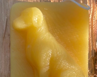 May include: A yellow beeswax candle shaped like a dog sitting down. The candle has a detailed design and is made of natural beeswax.