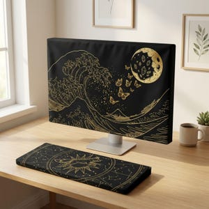 Peut inclure: Une housse d'écran d'ordinateur noire et un repose-poignet rectangulaire assorti, tous deux ornés de motifs dorés. La housse présente une grande vague, des papillons et une lune, tandis que le repose-poignet montre un renard dans un soleil et des constellations.