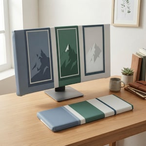 Puede incluir: Una funda para monitor de ordenador y un reposamuñecas para teclado a juego con un diseño de paisaje de montaña. La funda muestra tres paneles verticales en azul, verde y blanco, cada uno con un gráfico de pico de montaña.
