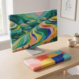 Könnte beinhalten: Ein Computermonitor und eine passende Tastatur-Handballenauflage mit einem lebendigen, abstrakten Landschaftsgemälde von Reisterrassen in Grün-, Gelb-, Blau- und Rosatönen, mit kleinen Silhouetten von Figuren, die einen Pfad entlanggehen.