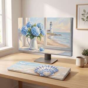 May include: A computer monitor displaying a painting of blue hydrangeas in a white pitcher next to a window overlooking a lighthouse and beach. A matching keyboard wrist rest features a painted beach scene with a large blue and white seashell.