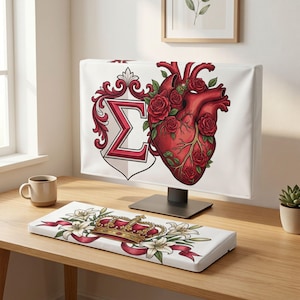 Könnte beinhalten: Eine Computermonitor-Abdeckung mit einem roten anatomischen Herzen, das von roten Rosen und dem griechischen Buchstaben Sigma umrankt ist, sowie eine passende Tastatur-Handballenauflage mit einer goldenen Krone, weißen Lilien und roten Bändern.
