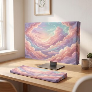 Può includere: Una copertura per monitor di computer e un poggiapolsi rettangolare abbinato per tastiera, entrambi caratterizzati da un'illustrazione digitale continua di nuvole morbide e soffici in tonalità pastello di rosa, lavanda e azzurro.
