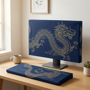 Può includere: Una copertura per monitor di computer blu scuro e un poggiapolsi rettangolare abbinato per tastiera, entrambi caratterizzati da un'illustrazione a linee dorate di un drago con squame e baffi fluenti su uno sfondo blu scuro.