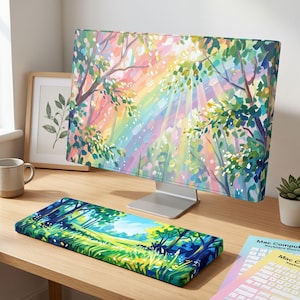 May include: A computer monitor and a matching keyboard wrist rest featuring a vibrant, impressionistic forest scene with colorful trees, foliage, and light rays. The monitor displays a rainbow-hued woodland, while the wrist rest shows a green meadow.