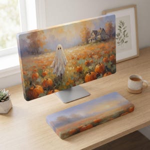 Può includere: Un monitor per computer e un poggiapolsi per tastiera abbinato con un dipinto impressionista di un fantasma bianco in un campo di zucche arancioni, con fogliame autunnale e una casa sullo sfondo sotto un cielo tenue.
