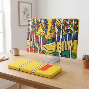 May include: A computer monitor cover and a matching keyboard wrist rest featuring a vibrant, stylized forest landscape with white birch trees, yellow background, and geometric patches of red, blue, and green foliage in a bold, graphic art style.