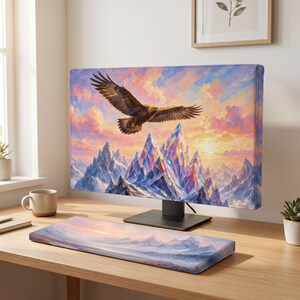 May include: A computer monitor and a matching keyboard wrist rest featuring a vibrant landscape print of a golden eagle soaring above jagged, snow-capped mountains against a colorful sunset sky with shades of pink, orange, and purple clouds.