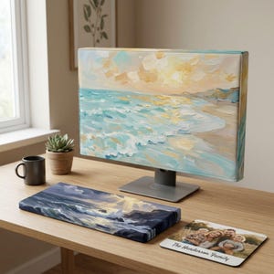 Puede incluir: Una funda para monitor de ordenador con una pintura impresionista de playa en tonos azules y dorados, un reposamuñecas rectangular a juego con una escena oceánica oscura y una alfombrilla de ratón cuadrada con una foto familiar y el texto The Henderson Family.