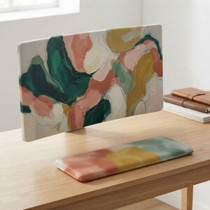 May include: A rectangular computer monitor stand and a matching rectangular keyboard wrist rest. Both items feature an abstract painted design with thick, textured brushstrokes in shades of forest green, muted peach, mustard yellow, and cream white.
