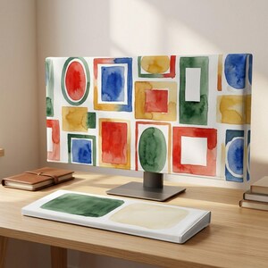 May include: A computer monitor cover and a matching keyboard cover featuring a watercolor pattern of various geometric shapes in red, blue, green, and yellow. The shapes include rectangles, squares, and ovals arranged in a repeating grid design.