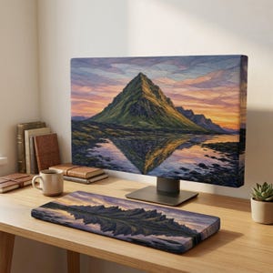Peut inclure: Un écran d'ordinateur affichant une image de paysage représentant une montagne verte se reflétant dans l'eau au coucher du soleil, accompagné d'un tapis de bureau rectangulaire assorti, posé sur un bureau en bois avec une tasse et des livres.