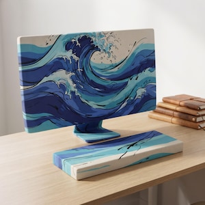 May include: A computer monitor and a matching keyboard wrist rest featuring a stylized graphic print of ocean waves in shades of dark blue, light blue, and white. The design covers the entire front surface of the monitor and the wrist rest.