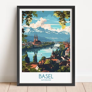 May include: A framed travel poster featuring a stylized illustration of Basel, Switzerland. The scene depicts a river flowing through the city with red-roofed buildings, a prominent church with twin spires, and snow-capped mountains under a blue sky.