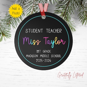 May include: A round black ornament with a red ribbon hanger featuring white text that reads STUDENT TEACHER, 1ST GRADE, MADISON MIDDLE SCHOOL, 2025-2026, and the name Miss Taylor in a multi-colored gradient font, enclosed by a thin cyan circle.